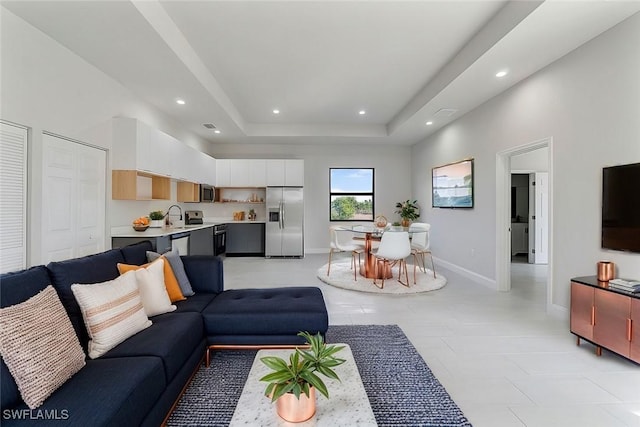 living room with recessed lighting, a raised ceiling, and baseboards