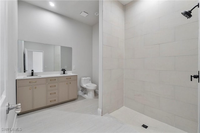 bathroom with double vanity, toilet, a sink, and tiled shower