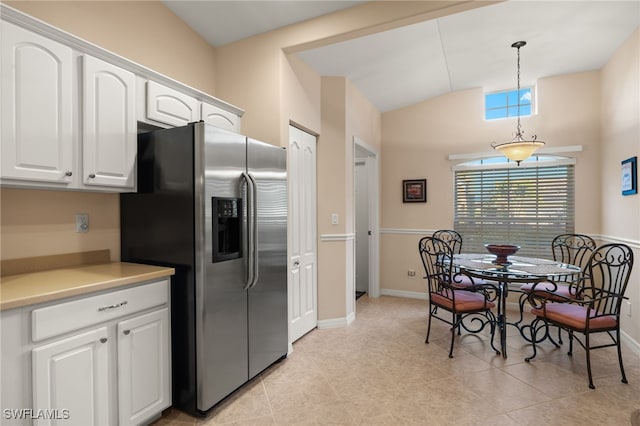 kitchen featuring vaulted ceiling, pendant lighting, white cabinetry, light tile patterned floors, and stainless steel refrigerator with ice dispenser