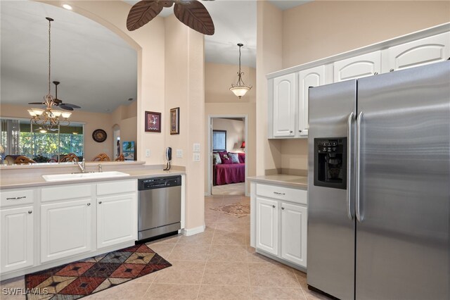 kitchen featuring light tile patterned flooring, decorative light fixtures, sink, white cabinets, and stainless steel appliances