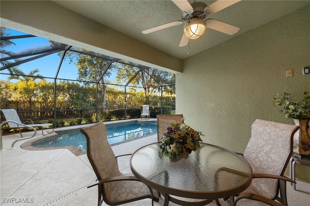 view of swimming pool with ceiling fan, glass enclosure, and a patio area