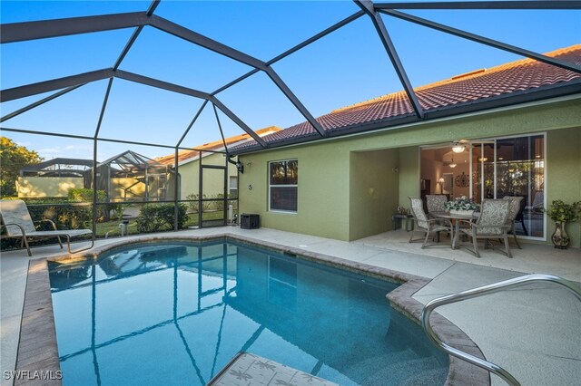 view of pool with central AC, a patio area, and glass enclosure