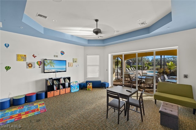 playroom featuring a tray ceiling, carpet floors, and ceiling fan