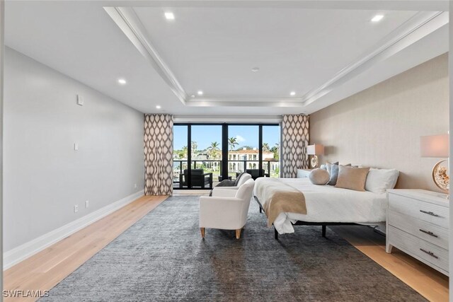 bedroom featuring baseboards, access to exterior, light wood-style flooring, and a raised ceiling