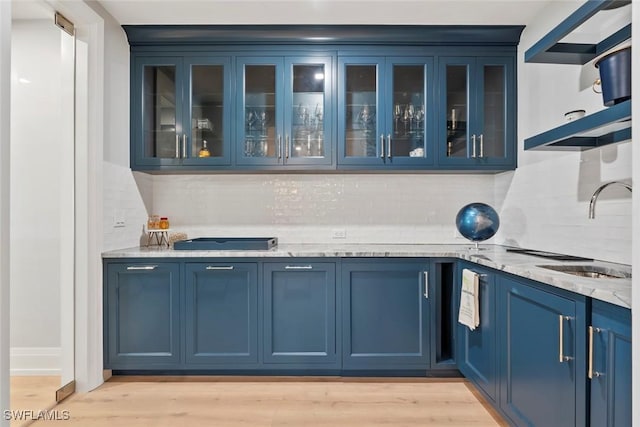 bar featuring a sink, light wood-style floors, and decorative backsplash