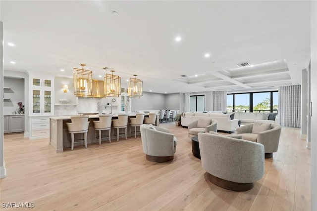 living area with light wood-style flooring, visible vents, recessed lighting, beam ceiling, and coffered ceiling