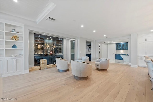 living room with visible vents, a bar, built in shelves, recessed lighting, and light wood-style floors