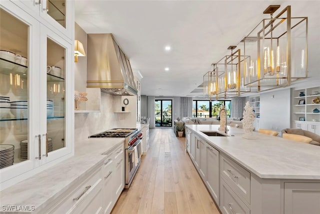 kitchen with open floor plan, a sink, double oven range, and extractor fan