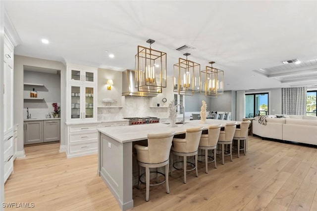 kitchen featuring a breakfast bar, decorative backsplash, a large island, and light wood-style floors