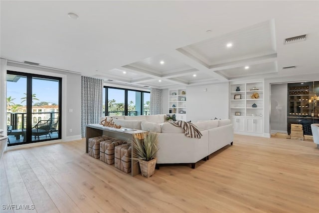 living room featuring light wood-style flooring, baseboards, built in shelves, beam ceiling, and coffered ceiling