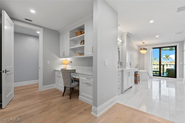office space featuring light wood-style flooring, visible vents, baseboards, recessed lighting, and built in study area