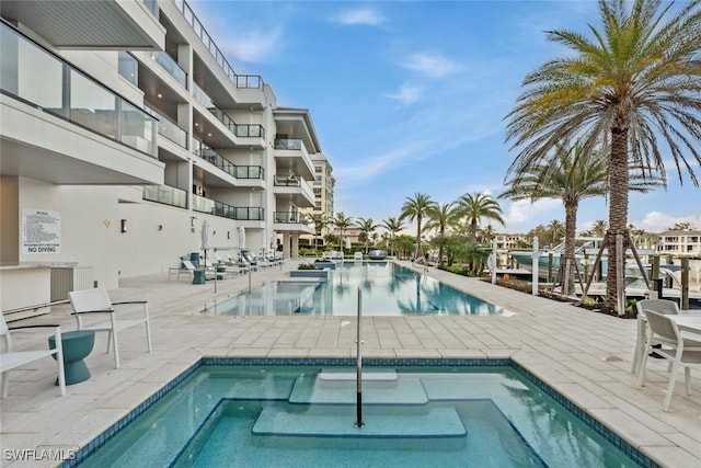 community pool with a community hot tub and a patio area