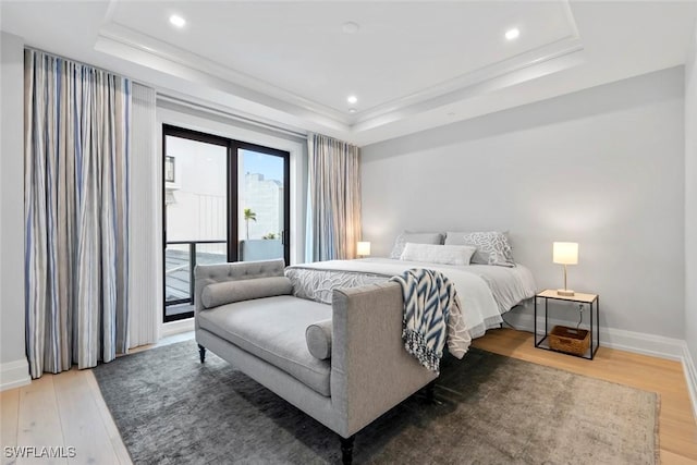 bedroom with a tray ceiling, recessed lighting, access to outside, baseboards, and light wood finished floors