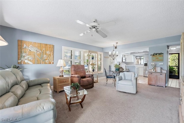 carpeted living room featuring ceiling fan with notable chandelier and a textured ceiling