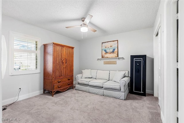 sitting room featuring a textured ceiling, light colored carpet, and ceiling fan