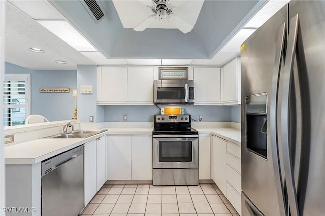 kitchen with appliances with stainless steel finishes, sink, light tile patterned floors, and white cabinets