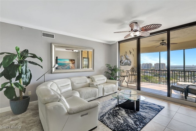 living room featuring light tile patterned flooring, crown molding, and a wall of windows