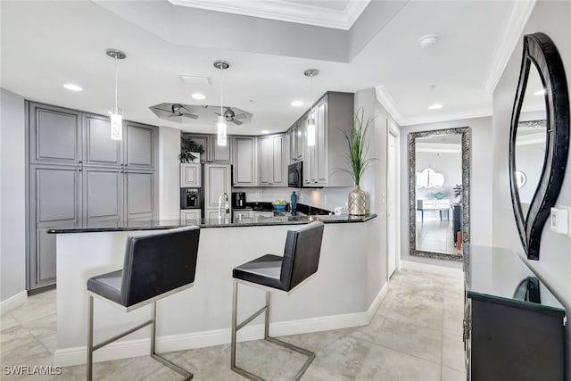 kitchen with a breakfast bar, gray cabinetry, crown molding, hanging light fixtures, and kitchen peninsula