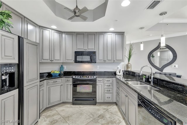 kitchen featuring sink, a raised ceiling, pendant lighting, dark stone counters, and black appliances