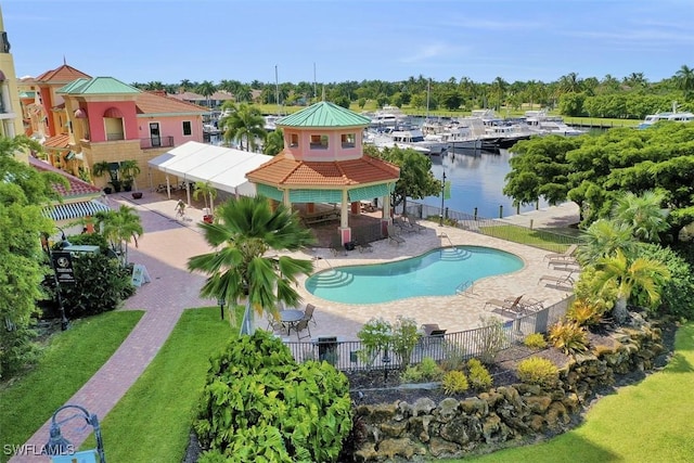 view of swimming pool featuring a patio, a water view, and a yard