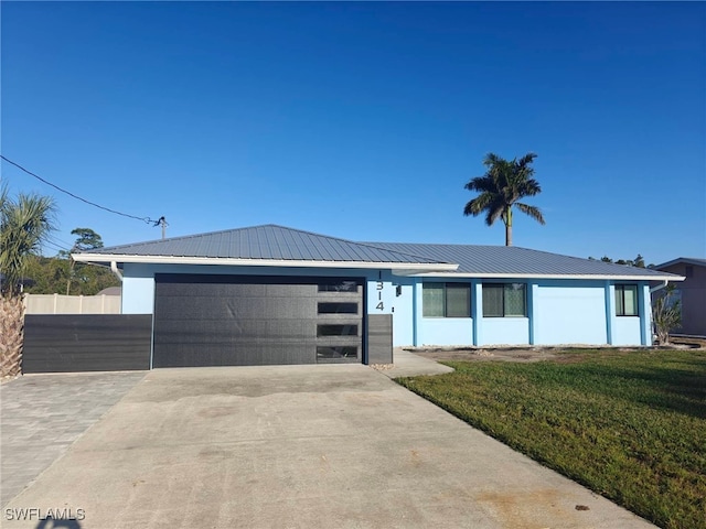 view of front of property featuring metal roof, a garage, concrete driveway, stucco siding, and a front lawn