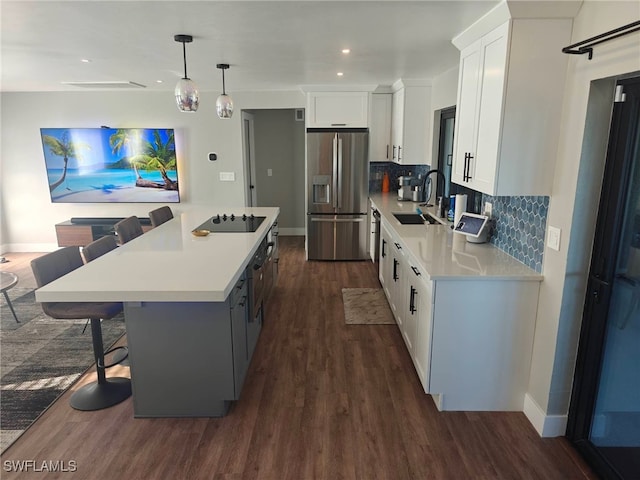 kitchen with stainless steel refrigerator with ice dispenser, sink, a kitchen island, pendant lighting, and white cabinets