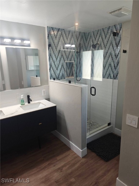 bathroom with walk in shower, vanity, tasteful backsplash, and hardwood / wood-style flooring