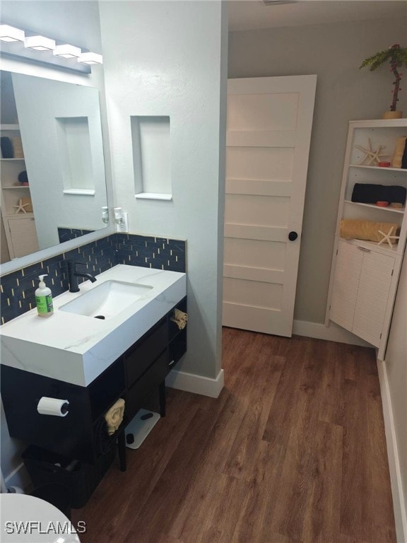 bathroom featuring wood-type flooring, backsplash, and vanity