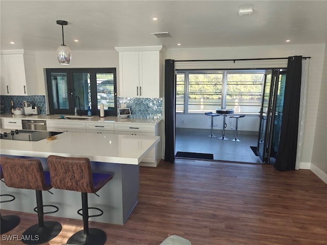 kitchen featuring sink, dark wood-type flooring, white cabinetry, hanging light fixtures, and decorative backsplash