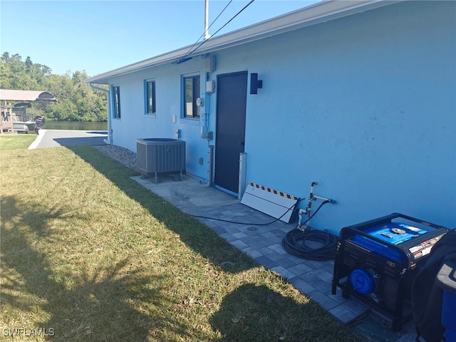 rear view of house with central AC, a yard, and stucco siding