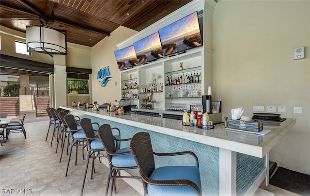 bar with beam ceiling, a high ceiling, and wooden ceiling