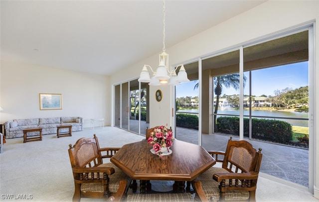 carpeted dining area with lofted ceiling, a notable chandelier, and a water view