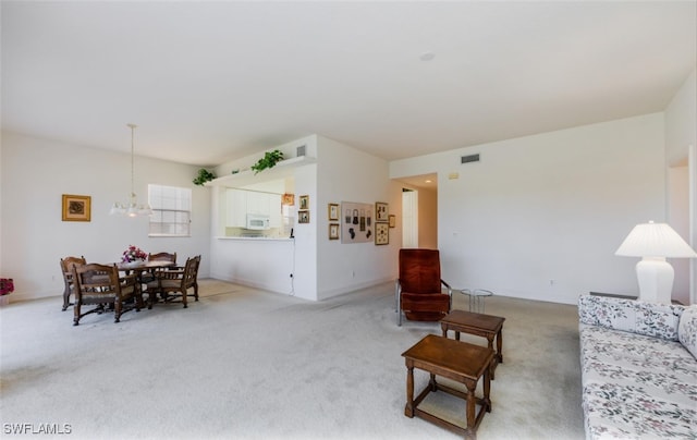 carpeted living room featuring an inviting chandelier