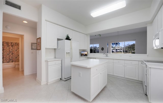 kitchen featuring a center island, white cabinetry, visible vents, white appliances, and light countertops
