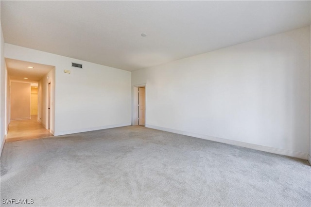 spare room with baseboards, light carpet, and visible vents