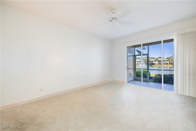 spare room with carpet floors, a ceiling fan, baseboards, and a water view