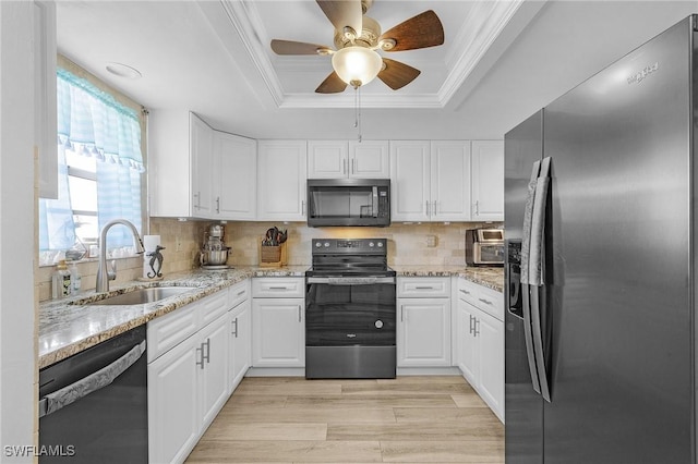 kitchen with ornamental molding, a sink, white cabinets, appliances with stainless steel finishes, and a raised ceiling