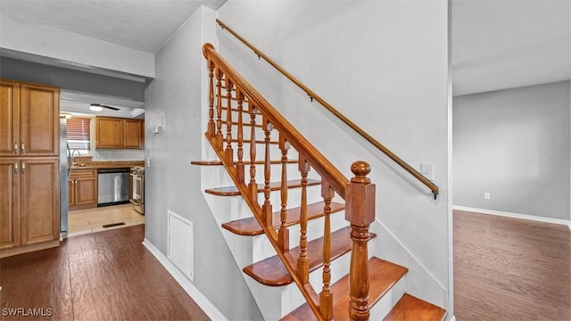 stairs with wood finished floors, visible vents, and baseboards