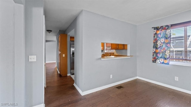 spare room featuring dark wood finished floors, visible vents, and baseboards