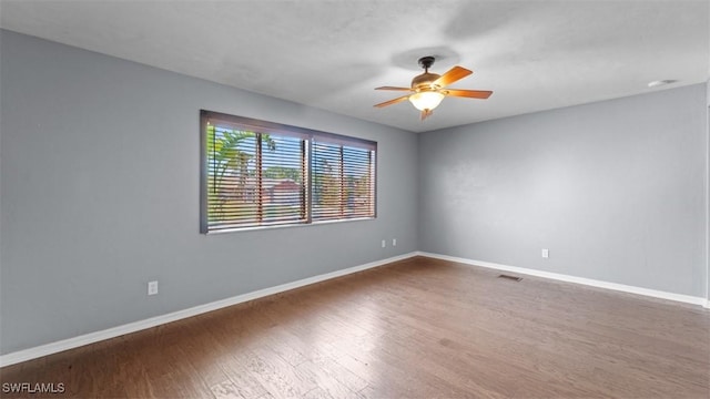 spare room featuring ceiling fan, baseboards, and wood finished floors