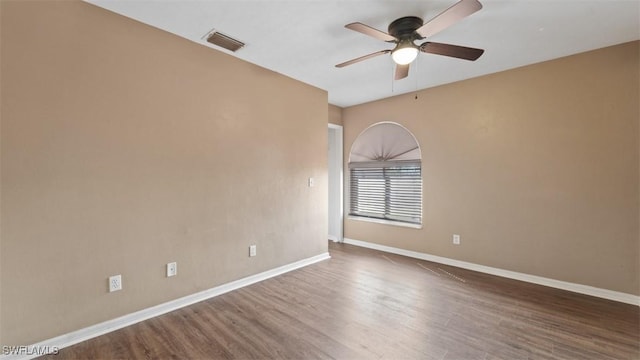 unfurnished room with ceiling fan, wood finished floors, visible vents, and baseboards