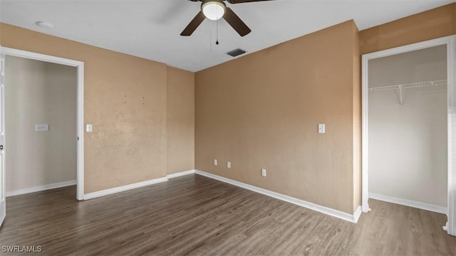 unfurnished bedroom featuring wood finished floors, a ceiling fan, visible vents, baseboards, and a closet