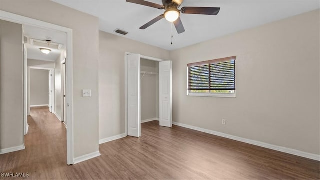 unfurnished bedroom featuring baseboards, visible vents, a ceiling fan, wood finished floors, and a closet