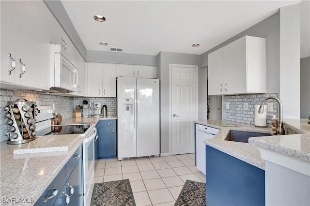 kitchen with blue cabinetry, white appliances, white cabinetry, and light stone countertops