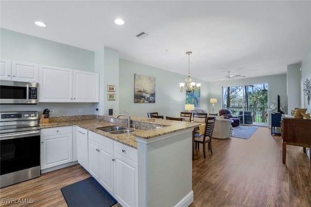 kitchen with pendant lighting, sink, white cabinets, kitchen peninsula, and stainless steel appliances