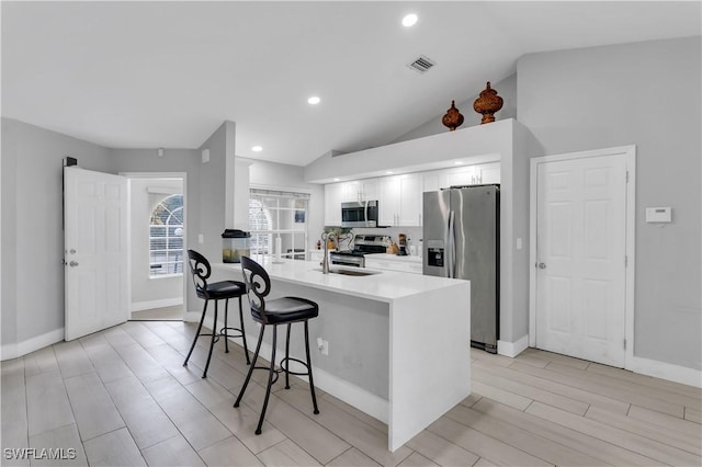 kitchen with appliances with stainless steel finishes, tasteful backsplash, sink, a breakfast bar area, and white cabinets