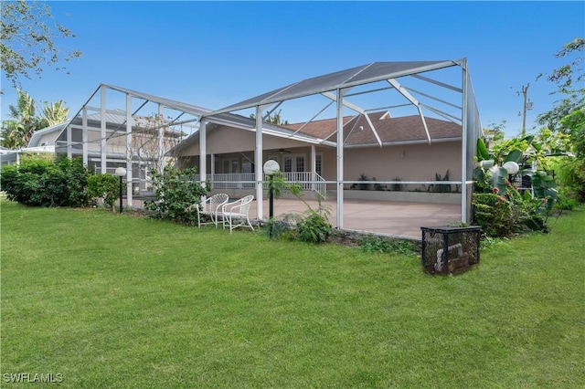 rear view of property with a lanai, a lawn, a patio, and ceiling fan