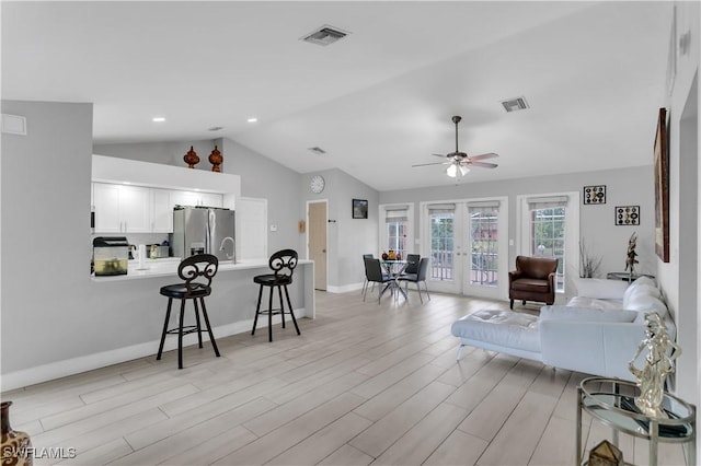 living room with sink, ceiling fan, light hardwood / wood-style floors, vaulted ceiling, and french doors