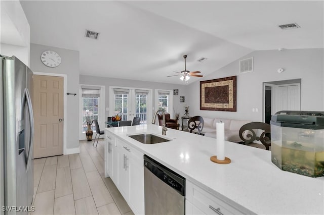 kitchen featuring stainless steel appliances, vaulted ceiling, sink, and white cabinets