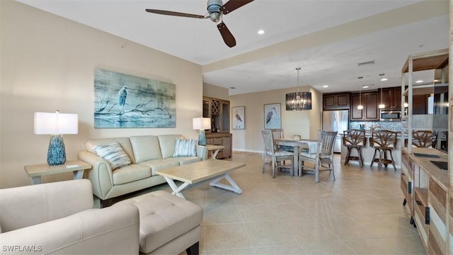 living room with light tile patterned floors and ceiling fan with notable chandelier